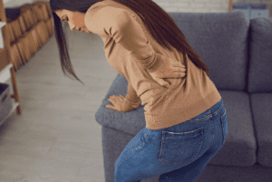 Young Woman Holding Onto Sofa With Lower Back Pain